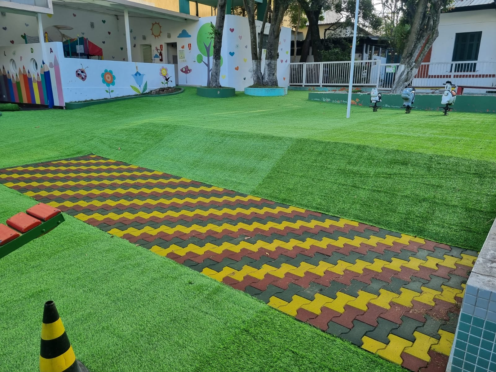 Área de recreação com grama sintética e piso colorido